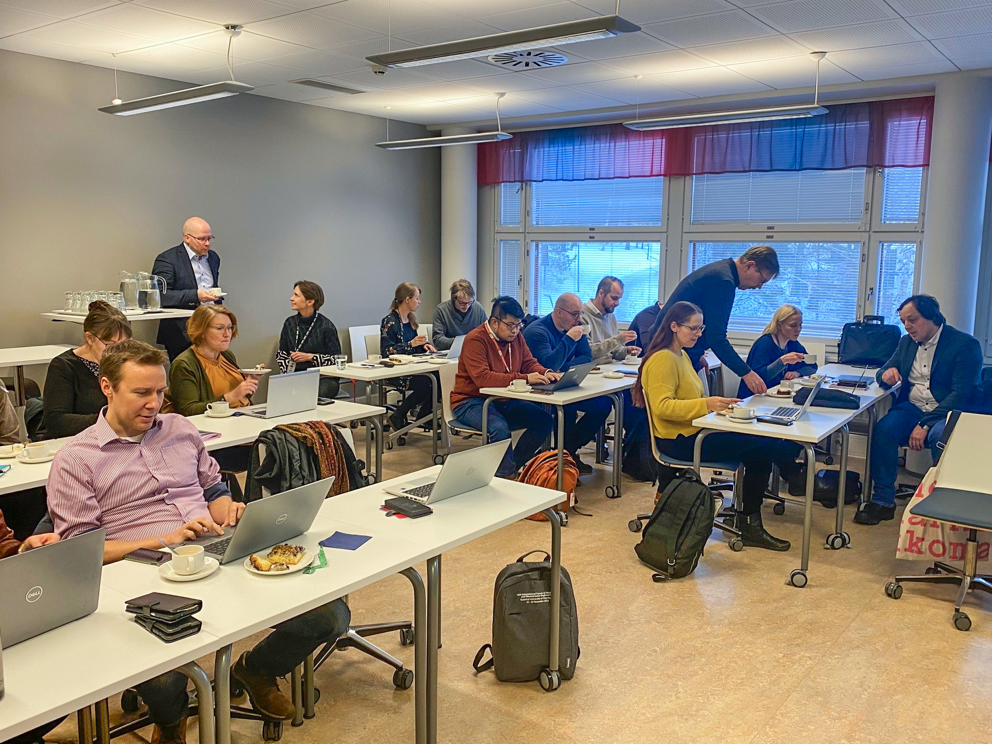 Keski-Suomen vetyverkoston jäseniä tammikuun tapaamisessa. Ihmiset istuvat Jyväskylän ammattikorkeakoulun luokkahuoneessa pöytien takana, läppärit edessään.